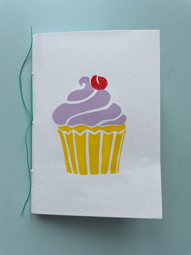 Håndsyet notesbog m. cup cake-tryk, lilla glasur